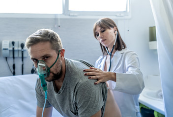 Wall Mural - Sick man Inhaling Through Oxygen Mask having a medical exam by female doctor at hospital