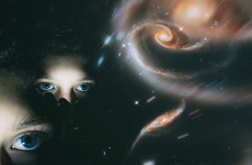 A young girl with a mystical look on the background of the starry sky of the galaxy. The concept of clairvoyance, mysticism. Elements of this image are provided by NASA. Double blurred exposure.