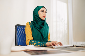 Wall Mural - serious young muslim businesswoman in traditional clothes working on computer at her office table