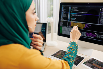 Wall Mural - young muslim software developer checking strings in programming code on computer screen