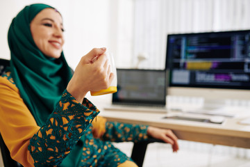 Wall Mural - happy young woman in traditional muslim dress drinking cup of coffee after finishing project