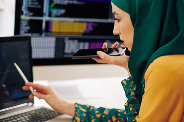 Wall Mural - muslim female developer checking programming code on laptop screen and recording voice message for c