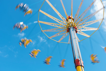 carousel in motion in theme park with blue sky background