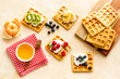 Belgian waffles with creamy cheese and berries on beige background top-down