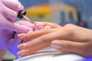 manicurist master is covering painting client's nails shellac, hands closeup. professional manicure 