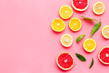 Citrus slices frame - lemons, grapefruits, leaves - on pink background top-down copy space