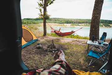 Wall Mural - person view couple resting at camping woman laying in hammock with beautiful view of forest lake