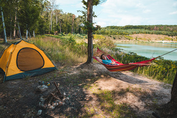 woman laying on hammock at camp near lake summer hiking concept