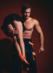 Firefighter sexy body muscle man holding saved sexy woman. Intimate relationship and sexual relations. Hot sexy Firefighter. Superhero. Passion and sensual touch.