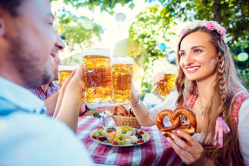 Wall Mural - Couple clinking glasses with huge amounts of beer in Bavarian pub