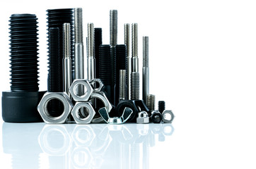 Metal bolts and nuts on white background. Fasteners equipment. Hardware tools. Stud bolt, hex nuts, and hex head bolts in workshop. Threaded fastener use in automotive engineering. Hexagonal bolt.