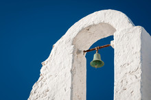 Traditional White Stucco Greek Island Church Bell Tower Standing Against Vibrant Blue Sky In Mykonos, Greece