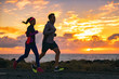 © Maridav - Running people training cardio together active friends jogging in early morning dawn sunrise on beach. Run fit couple runners woman and man running outdoor. Silhouettes of two athletes working out.
