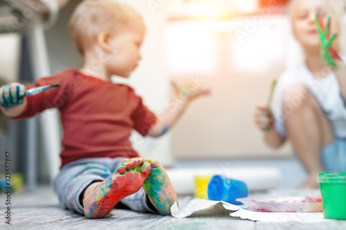 Adorable Cute Caucasian Little Blond Siblings Children Enjoy Having Fun Painting With Brush And Palm At Home Indoors Cheerful Happy Kids Smiling Drawing Masterpiece Art Picture Messy Dirty Room Stock Photo