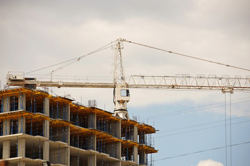 Tower cranes work during the construction of a multi-story building. New apartments for residents and premises for offices. Risky work at height. Lifting heavy building materials. City development