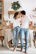 © Kateryna - Stylishly dressed in casual wear happy couple hugging near the table in the kitchen