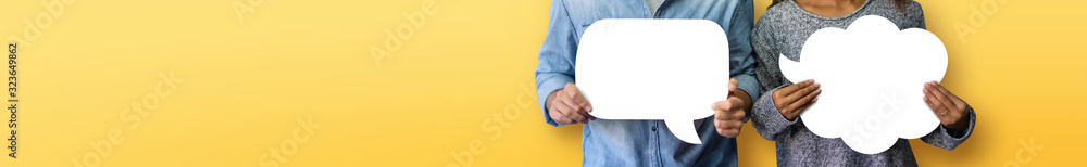 Couple holding white Speech Bubbles on yellow or orange isolated background. Banner, panoramic view for web. - obrazy, fototapety, plakaty 