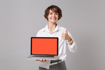 Funny business woman in white shirt posing isolated on grey background. Achievement career wealth business concept. Mock up copy space Hold laptop pc computer with blank empty screen showing thumb up.