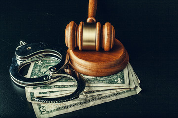 Wall Mural - Bribe concept. Dollar banknotes, handcuffs and gavel on dark black table