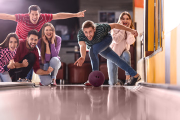 Canvas Print - Young man throwing ball and spending time with friends in bowling club