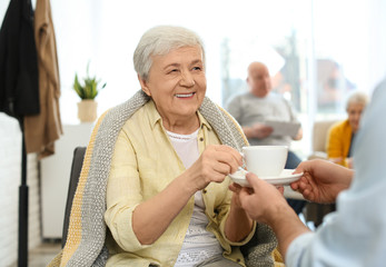 Canvas Print - Care worker giving drink to elderly woman in geriatric hospice