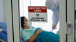 © Kobkit - Restricted area : Authorized personal area signage in front of control room with infected female patient and doctor in protective suit inside.