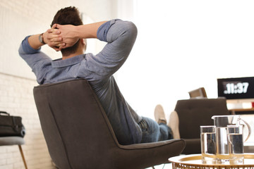 Wall Mural - Young man relaxing in comfortable chair at workplace