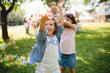 © Halfpoint - Small children standing outdoors in garden in summer, playing.