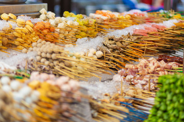 Traditional fried chinese food on sticks at night street vendor market