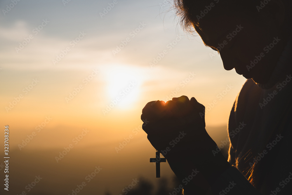 Silhouette of young  human hands praying with a  cross at sunrise, Christian Religion concept background. - obrazy, fototapety, plakaty 