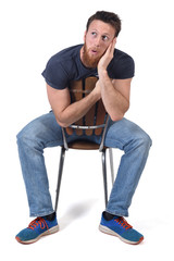 Wall Mural - man sittin on a chair with expression of forgetfulness or surprise on white background