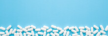 White Pills On Light Pastel Blue Table. Drugs Banner. Medical, Pharmacy And Healthcare Concept. Closeup. Empty Place For Text Or Logo. Top Down View.