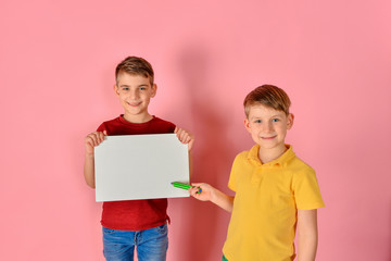 One boy holds a white board for inscription, the other shows a l