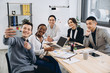 © anatoliycherkas - Multicultural group of professional business people making selfie in modern office