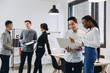 © anatoliycherkas - African businesswoman and Asian businessman using a laptop with interracial group of business men & women team