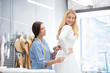 © pressmaster - Horizontal portrait of professional seamstress fitting wedding gown for client during try-on in modern bridal shop