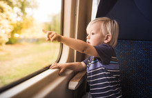 Little Curious Child Riding A Train Looking Out Window Pointing. 