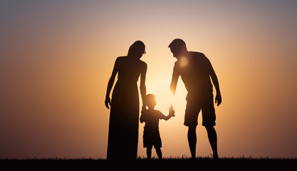 Wall Mural - Mother, father, child walking together at sunset. Happy loving family, parenting concept. 