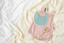 Pink Bodysuit And  Bib On Knitted Blanket. Set Of  Kids Clothes And Accessories  On Bed. Fashion Newborn. Flat Lay, Top View