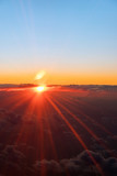 Fototapeta Góry - Sunset above the clouds. The view of the sunset from the plane. Rays of the sun through the clouds. Выделите текст, чтобы посмотреть примеры