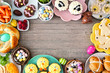 Easter table scene with a selection of breads, desserts and treats. Top view frame over a wood background. Spring holiday food concept.