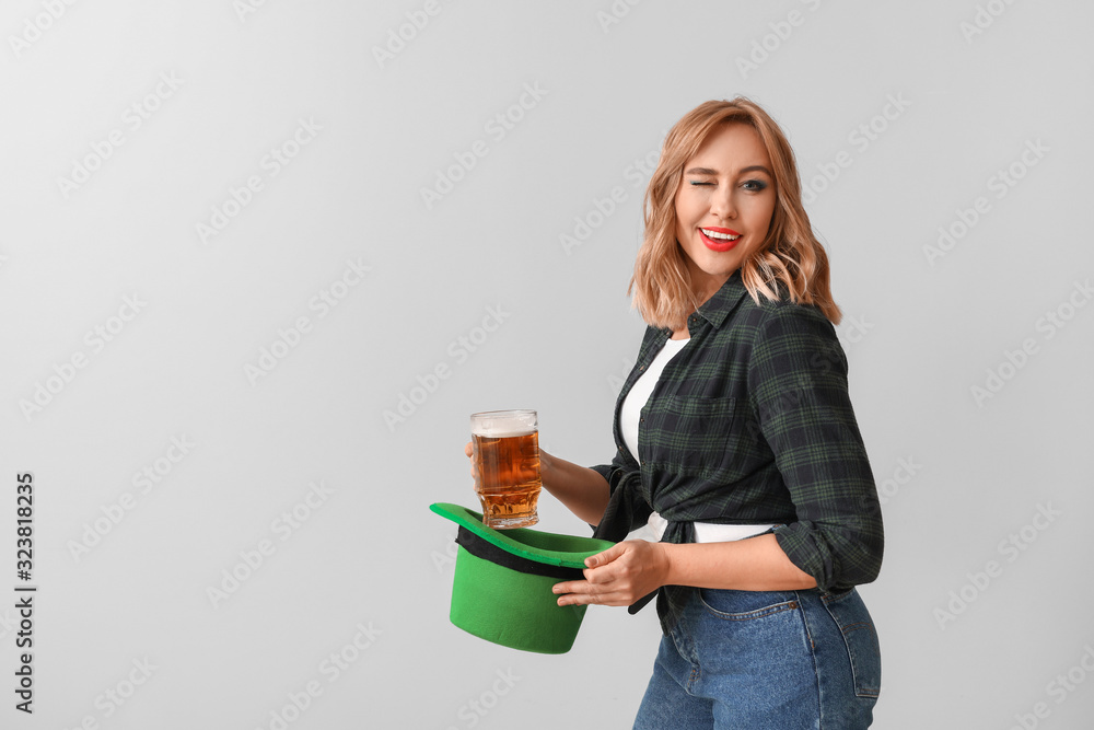 Beautiful young woman with beer on light background. St. Patrick's Day celebration