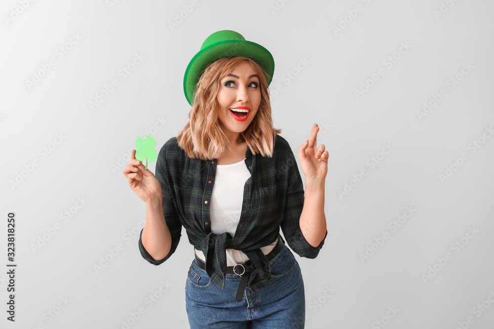 Beautiful young woman with paper clover on light background. St. Patrick's Day celebration