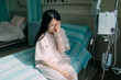 © PR Image Factory - asian korean woman patient in hospital room sitting on bed sick and injured feeling sad and depressed. illness lady with saline drip bag on hand covering face. sunshine through window bright indoor