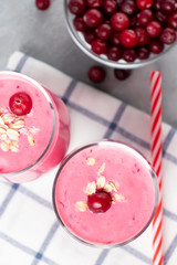 Wall Mural - Two glasses with freshly homemade smoothie of yogurt, oatmeal and cranberries on a gray table. Healthy eating concept, vertical flatlay