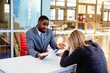 © Carlos David - Portrait of a young man in business suit with female client or business woman  explaining contract in office meeting
