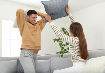 Wall Mural - Happy couple having pillow fight in living room