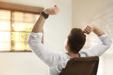 Wall Mural - Young man relaxing near window at home, back view