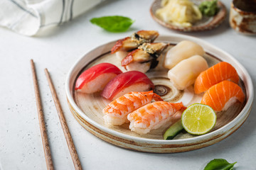 Wall Mural - Set of sushi and maki on plate with soy sauce and chopsticks on white background. Top view with copy space