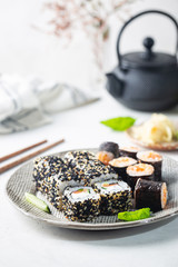 Wall Mural - Set of sushi and maki on plate with soy sauce and chopsticks on white background. Top view with copy space